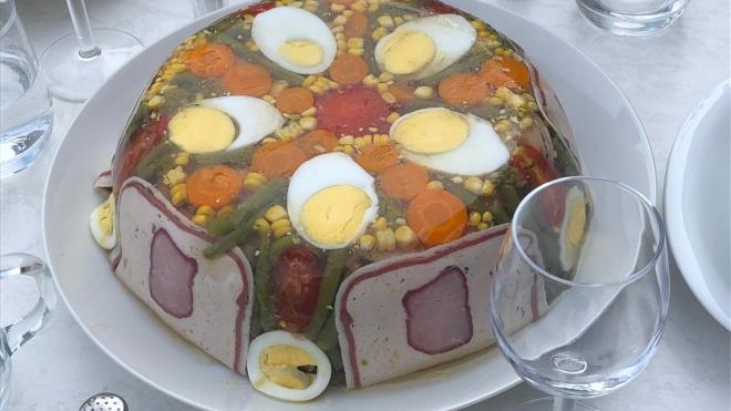 A plate with Eggs and Pork, corn and stuff made of jello seems to be giant on a plate.