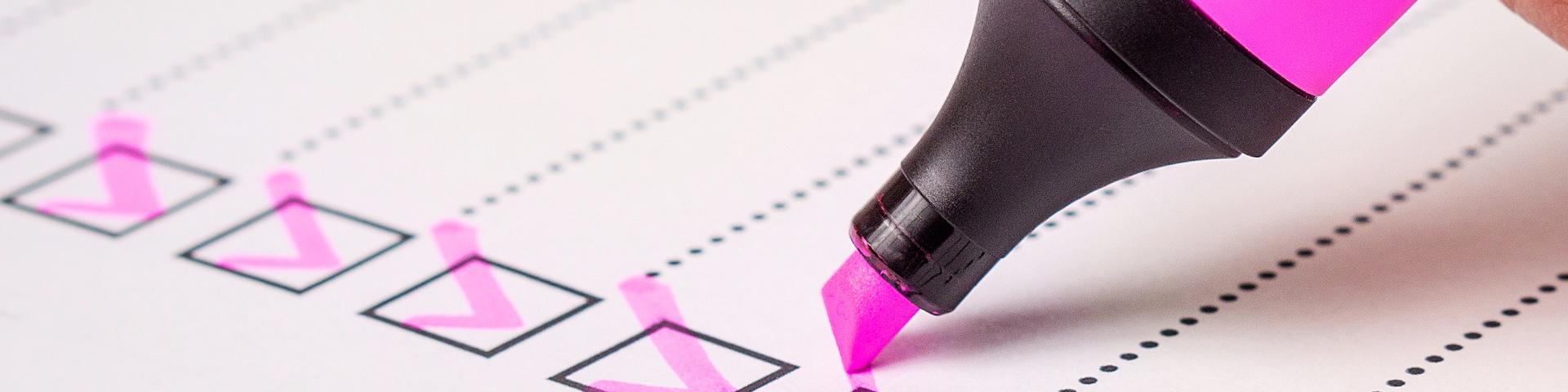 Nahaufnahme einer Checkliste auf der mit rosa Textmarker nach und nach die Checkkästchen abgehakt werden.