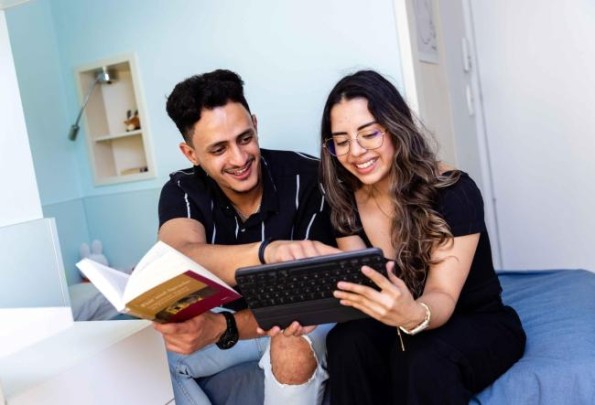 Bild zeigt zwei Studierende im Wohnheimzimmer, die gemeinsam lernen