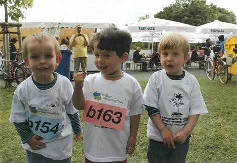 Drei Kleinkinder mit Startnummern bei einem Kindermarathon.