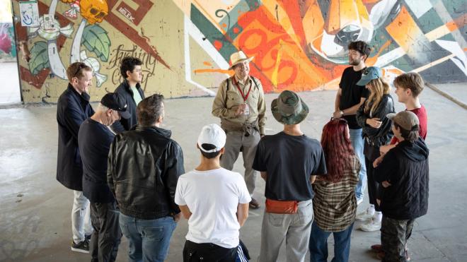 A group stands in a circle, looking at a tourguide.