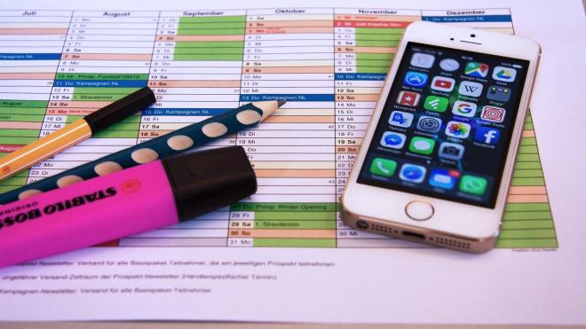 Printed time table with a phone and pens lying around