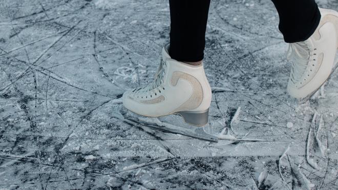 two white skates on ice. You can only see the feet in the skates and they are in the process of moving
