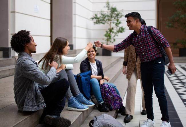 Das Bild zeigt junge Menschen, die sich freundlich begrüßen / The picture shows young people greeting each other in a friendly way