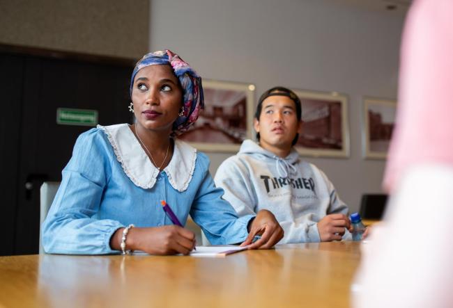 Picture shows two students listening to a side conversion