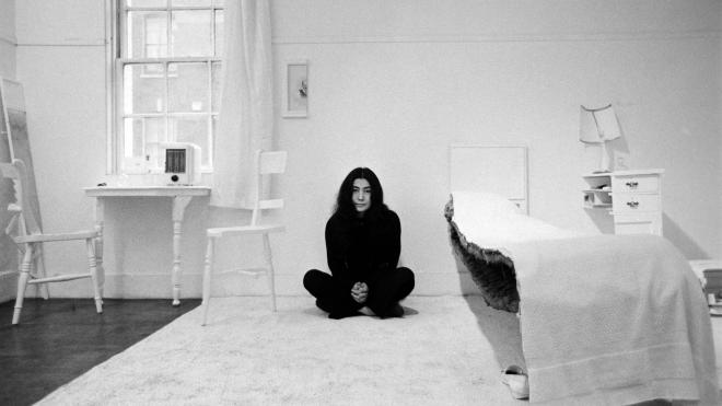 Yoko Ono sits cross-legged in the centre of a room