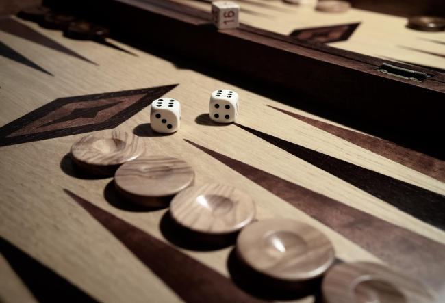 A backgammon set made of wood. The game pieces and two dice are visible.