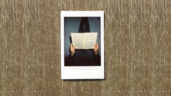 A Polaroid of a person with a book on the knees.