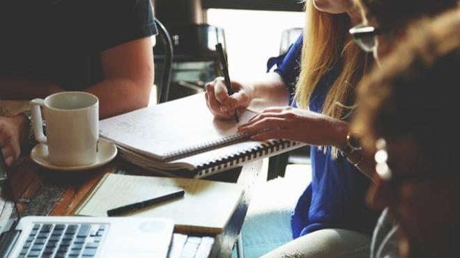 Students talking and writing together at a table with coffee